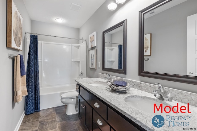 bathroom with toilet, a sink, double vanity, and baseboards
