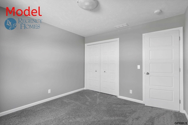 unfurnished bedroom with a textured ceiling, a closet, dark carpet, baseboards, and visible vents