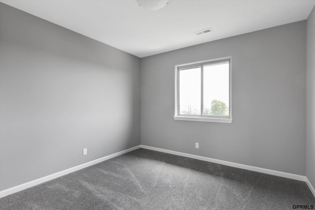 empty room featuring dark carpet, baseboards, and visible vents