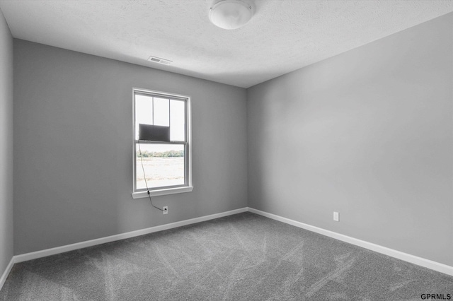 carpeted empty room with baseboards, a textured ceiling, and visible vents