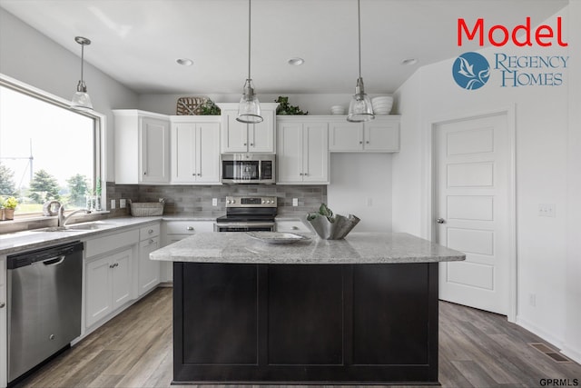 kitchen featuring stainless steel appliances, a sink, backsplash, white cabinetry, and wood finished floors