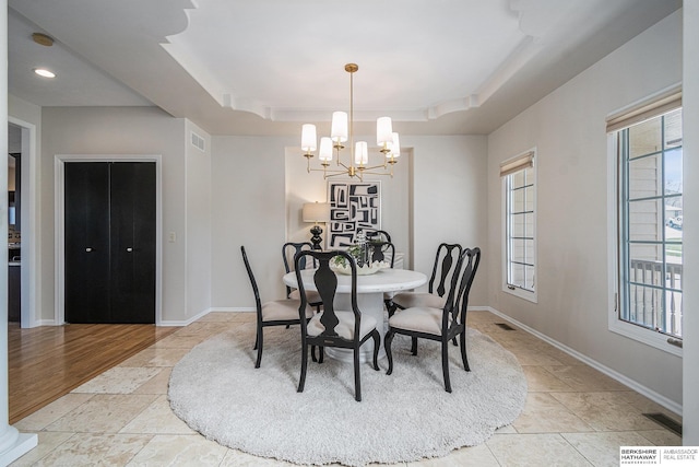 dining space with stone tile floors, visible vents, an inviting chandelier, and a tray ceiling