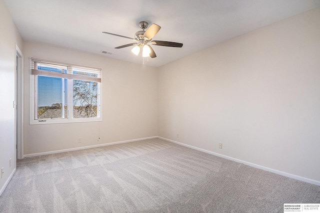 spare room with baseboards, visible vents, light colored carpet, and ceiling fan