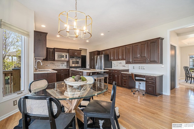 dining area featuring a chandelier, light wood finished floors, baseboards, and recessed lighting