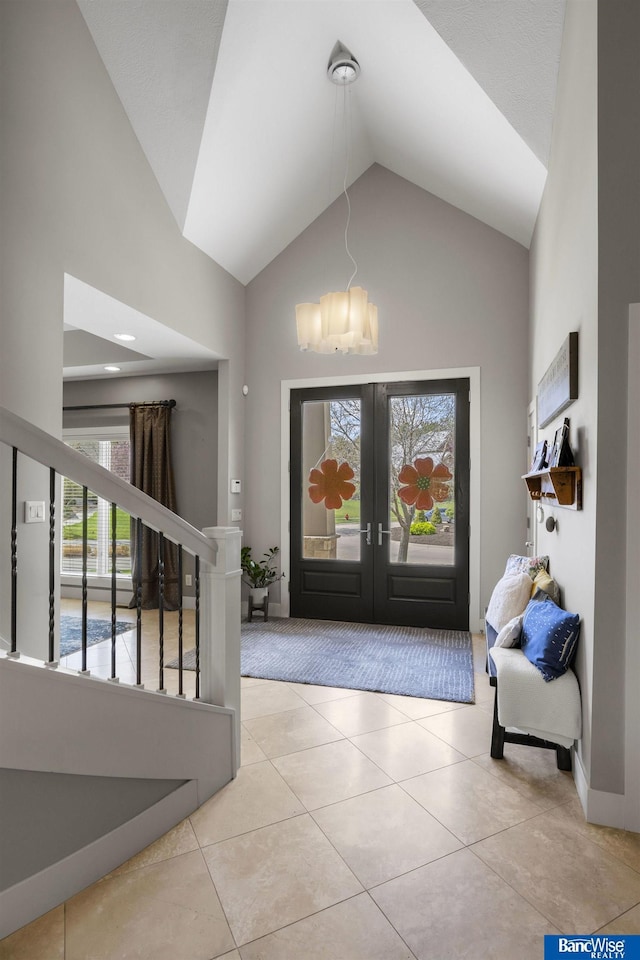 entrance foyer with tile patterned flooring, stairs, french doors, and an inviting chandelier