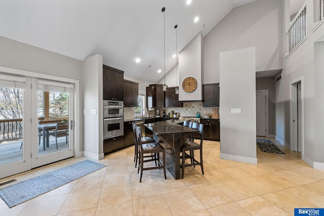 kitchen with high vaulted ceiling, dark brown cabinets, visible vents, and light tile patterned floors