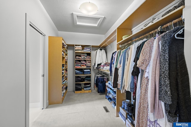 spacious closet featuring attic access, carpet floors, and visible vents