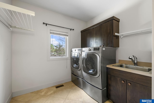 laundry room with washer and clothes dryer, a sink, baseboards, visible vents, and cabinet space