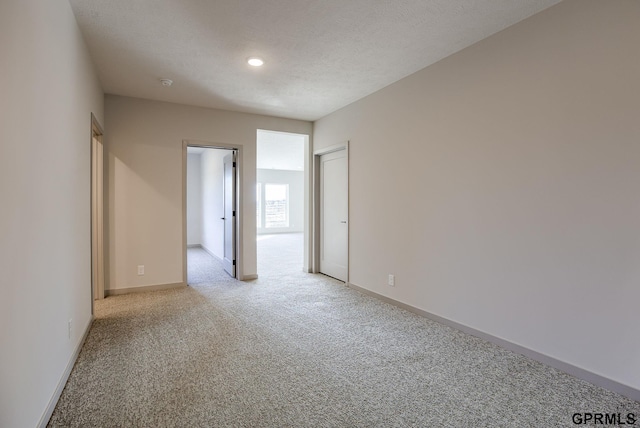 spare room with recessed lighting, baseboards, and light colored carpet
