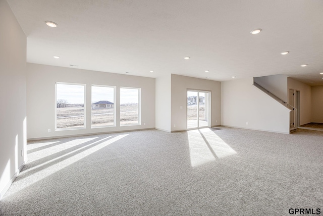 unfurnished living room with baseboards, light carpet, stairs, and recessed lighting