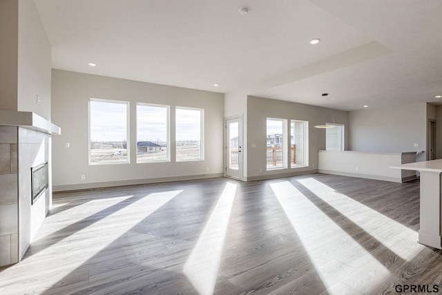 unfurnished living room featuring recessed lighting, baseboards, light wood-type flooring, and a fireplace