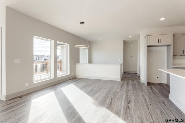 unfurnished living room featuring light wood finished floors, baseboards, visible vents, and recessed lighting