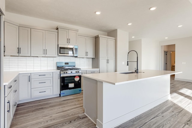 kitchen with recessed lighting, appliances with stainless steel finishes, a sink, and light wood-style flooring