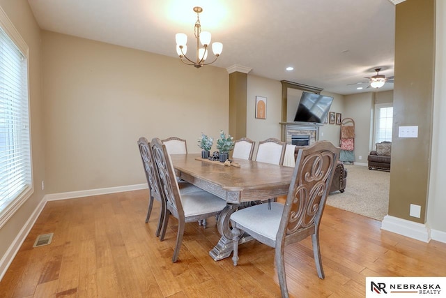 9441 Southern Sky Cir, Lincoln, NE 68505 - dining space featuring ceiling fan with notable chandelier, light wood-style floors, a fireplace, baseboards, and visible vents