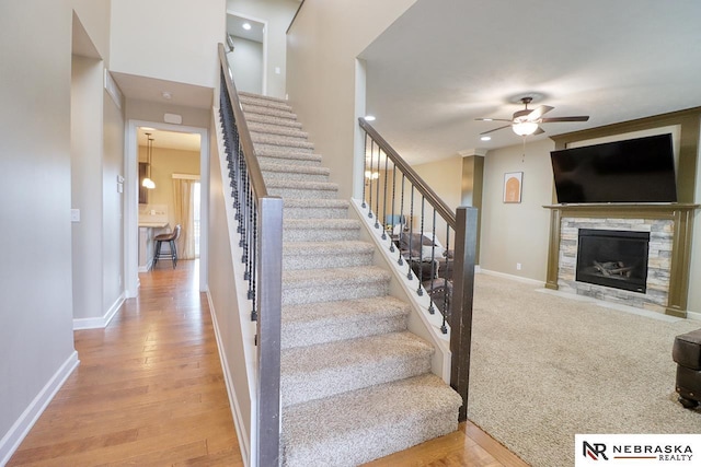 9441 Southern Sky Cir, Lincoln, NE 68505 - staircase with a fireplace with flush hearth, baseboards, wood finished floors, and ceiling fan
