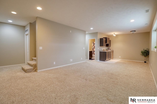 9441 Southern Sky Cir, Lincoln, NE 68505 - unfurnished living room with recessed lighting, baseboards, stairs, and light colored carpet