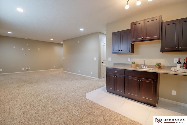 9441 Southern Sky Cir, Lincoln, NE 68505 - kitchen with dark brown cabinets, a sink, light carpet, light countertops, and recessed lighting