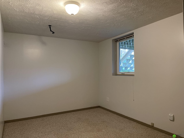 spare room featuring a textured ceiling, light colored carpet, and baseboards