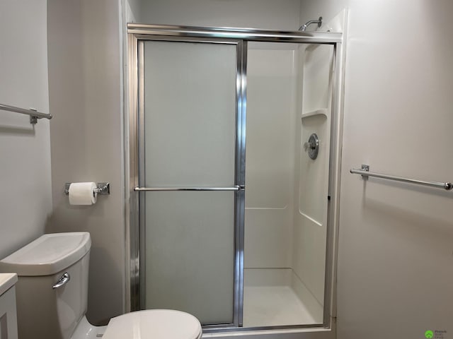 bathroom featuring toilet and a shower stall