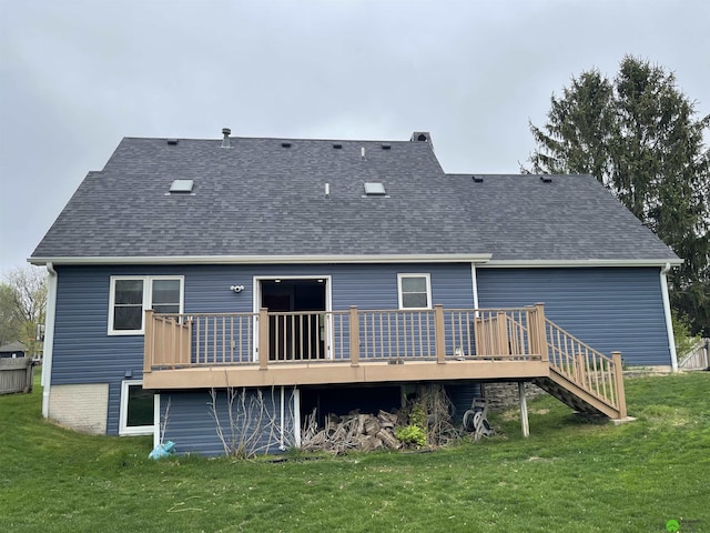 back of property featuring a wooden deck, a yard, and roof with shingles