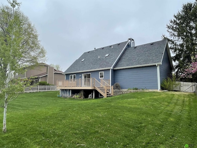 rear view of house with a deck, a yard, a shingled roof, and a fenced backyard