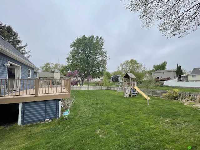 view of yard with a wooden deck, a playground, and fence