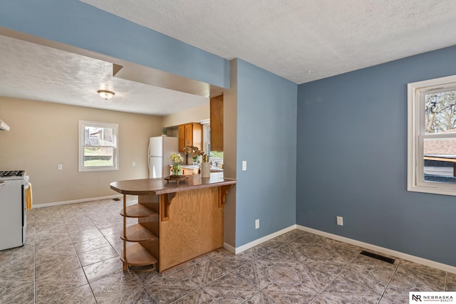 2725 Monroe St, Omaha, NE 68107 - kitchen with baseboards, visible vents, a textured ceiling, and white appliances