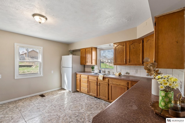 2725 Monroe St, Omaha, NE 68107 - kitchen featuring dark countertops, a sink, brown cabinets, visible vents, and freestanding refrigerator