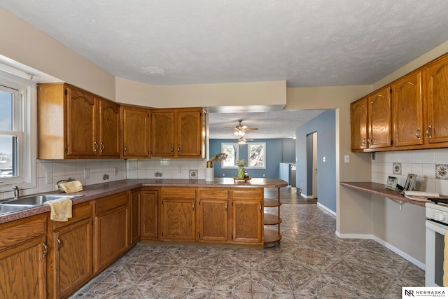 2725 Monroe St, Omaha, NE 68107 - kitchen featuring brown cabinetry, decorative backsplash, a peninsula, and a sink