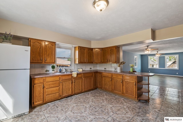 2725 Monroe St, Omaha, NE 68107 - kitchen featuring brown cabinets, tasteful backsplash, and freestanding refrigerator