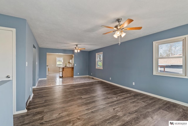 2725 Monroe St, Omaha, NE 68107 - unfurnished living room featuring wood finished floors, a textured ceiling, a ceiling fan, and baseboards