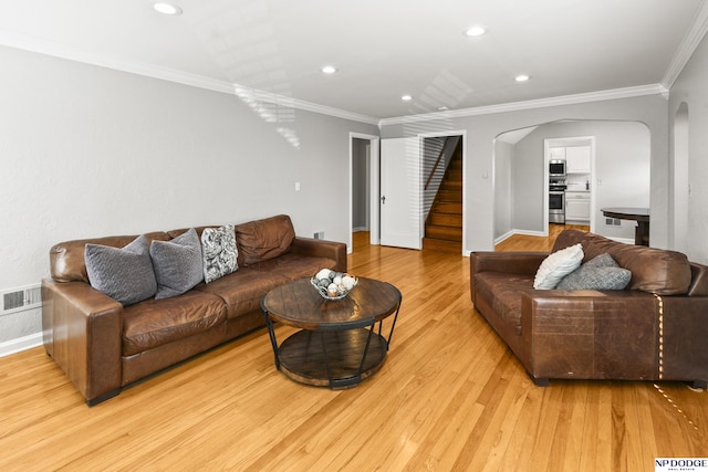 living room with arched walkways, light wood-type flooring, stairway, baseboards, and ornamental molding