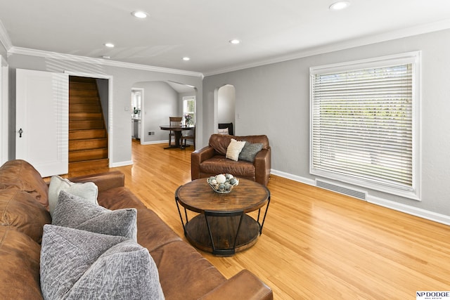 living room featuring crown molding, arched walkways, wood finished floors, and visible vents
