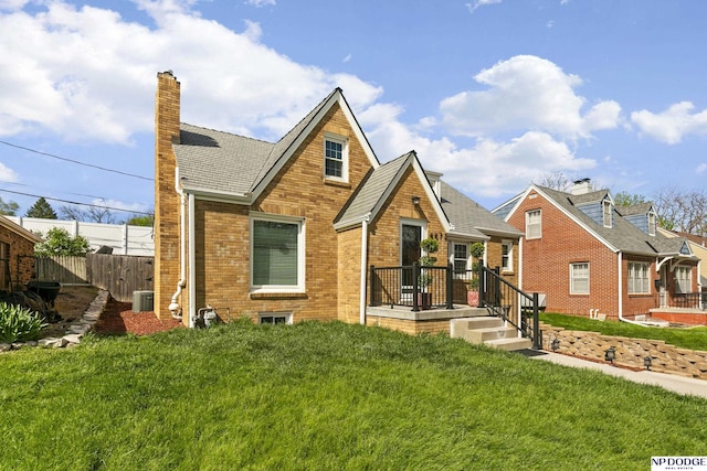 view of front of property featuring a chimney, a front yard, central air condition unit, brick siding, and fence