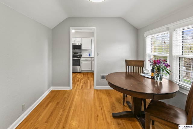 dining room with baseboards, lofted ceiling, light wood-type flooring, and visible vents