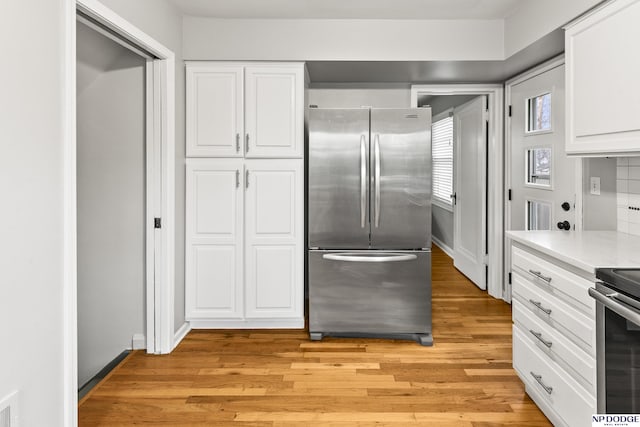 kitchen with light countertops, light wood-style flooring, appliances with stainless steel finishes, and white cabinetry
