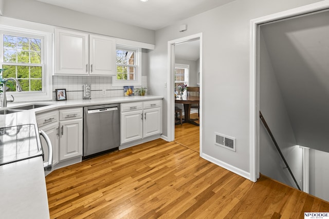 kitchen featuring visible vents, dishwasher, a sink, white cabinets, and light wood finished floors