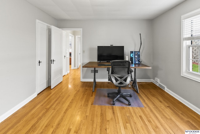 home office featuring baseboards, visible vents, and light wood finished floors