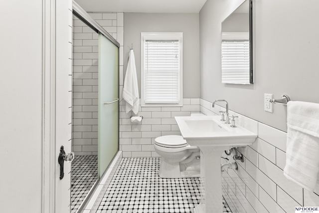 full bath featuring toilet, tile walls, a wainscoted wall, tile patterned floors, and a shower stall