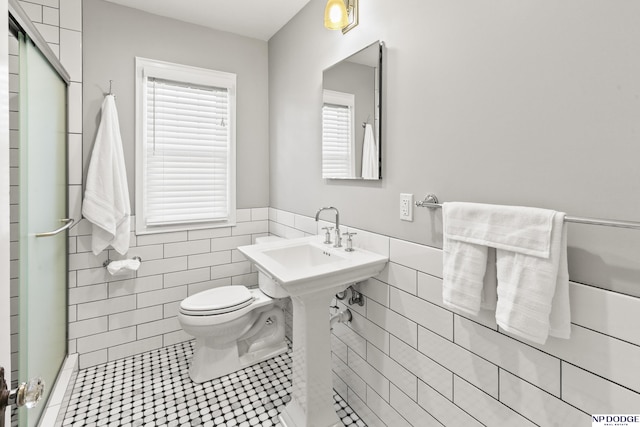 full bathroom featuring tile patterned flooring, toilet, a wainscoted wall, tile walls, and a shower