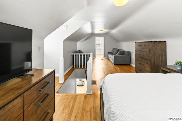 bedroom with baseboards, visible vents, light wood-type flooring, and lofted ceiling