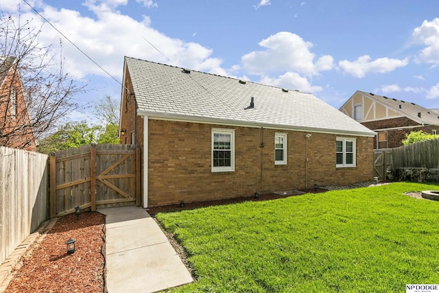 back of property with a yard, brick siding, a gate, and a fenced backyard