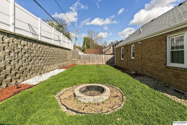 view of yard with a fenced backyard and a fire pit