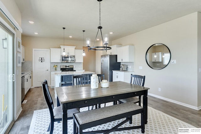 dining room featuring baseboards, wood finished floors, recessed lighting, and a notable chandelier