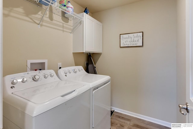washroom featuring baseboards, washing machine and clothes dryer, cabinet space, and light wood-style flooring