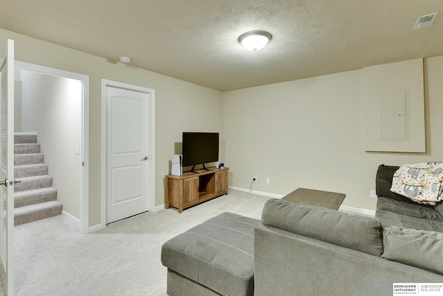 living area with stairway, a textured ceiling, light carpet, baseboards, and visible vents