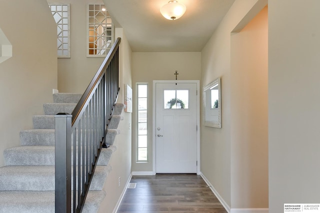 foyer entrance featuring stairway, baseboards, and wood finished floors