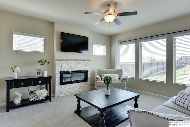 carpeted living room featuring a fireplace, baseboards, and ceiling fan