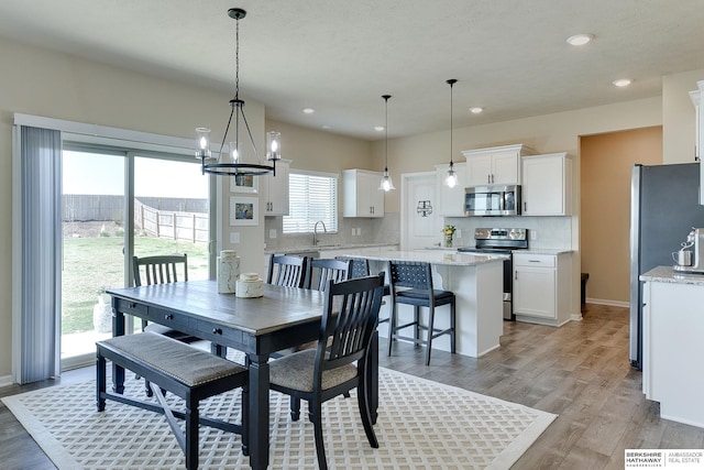 dining room featuring baseboards, recessed lighting, a chandelier, and light wood-style flooring