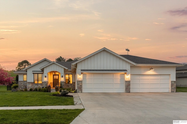 view of front of home with an attached garage, driveway, stone siding, and board and batten siding